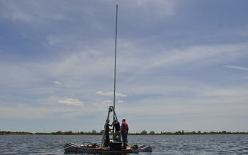 Scientists in a boat collecting a sediment core